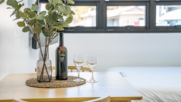 Una mesa con una botella de vino, dos copas y una planta.