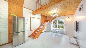 Eine moderne Küche mit einem Edelstahlkühlschrank, einer Holztreppe und einem Essbereich mit Tisch und Stühlen.
