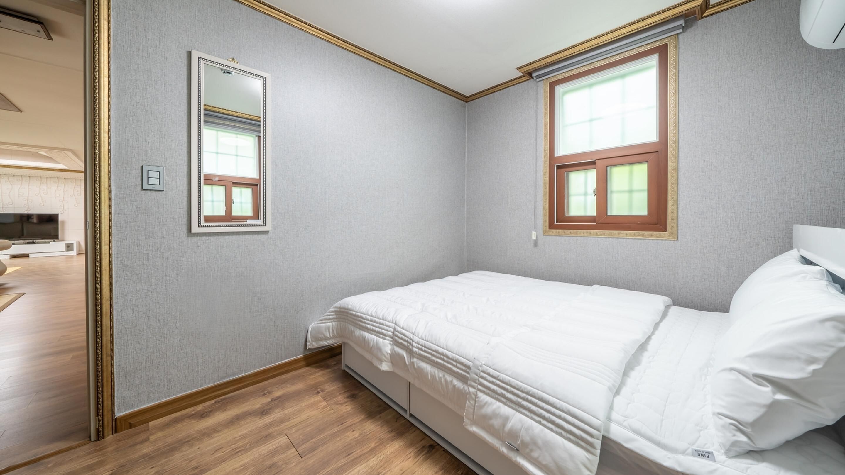 A bedroom with a bed, a window, and a mirror.