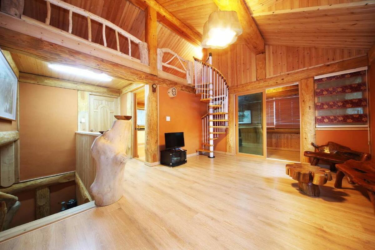 A spacious wooden interior with a spiral staircase, wooden furniture, and a television.