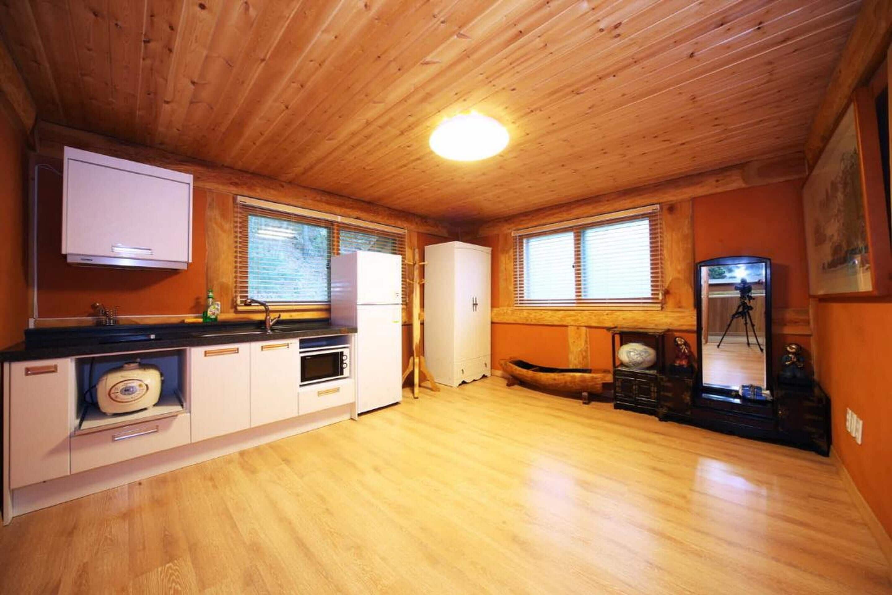 Une cuisine de taille réduite, dotée de meubles de rangement en bois, d’un four encastré et d’un réfrigérateur.