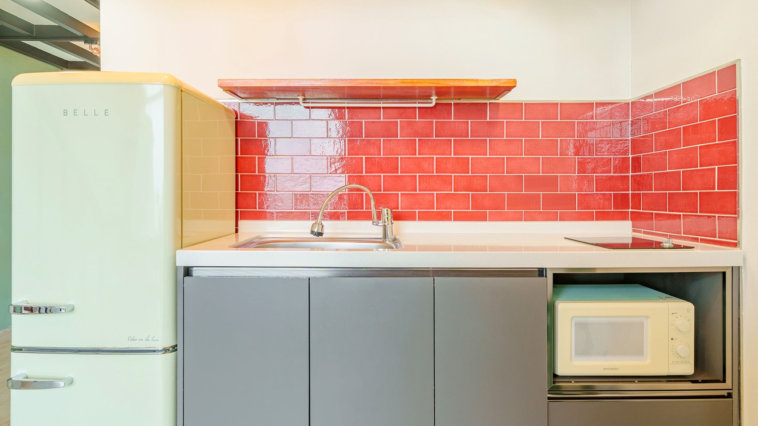 A compact kitchen with a white refrigerator, a sink with a chrome faucet, and a microwave on a countertop.