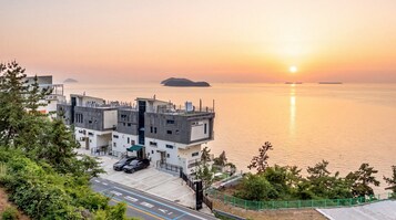 Edificio moderno con terraza en la azotea y vista al mar tranquilo al atardecer.