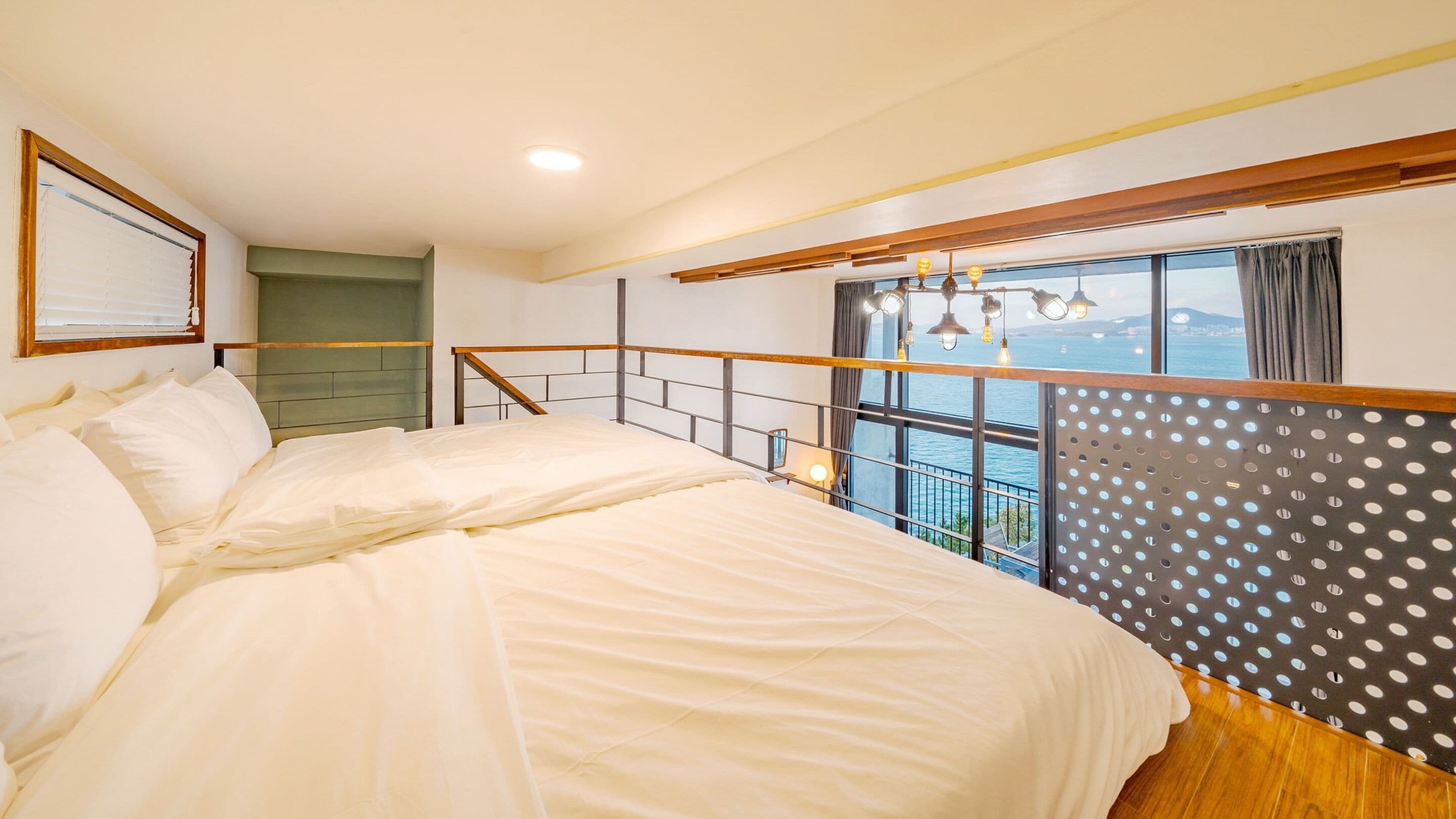 Un dormitorio con una cama grande, vista al mar y una ventana con cortina.
