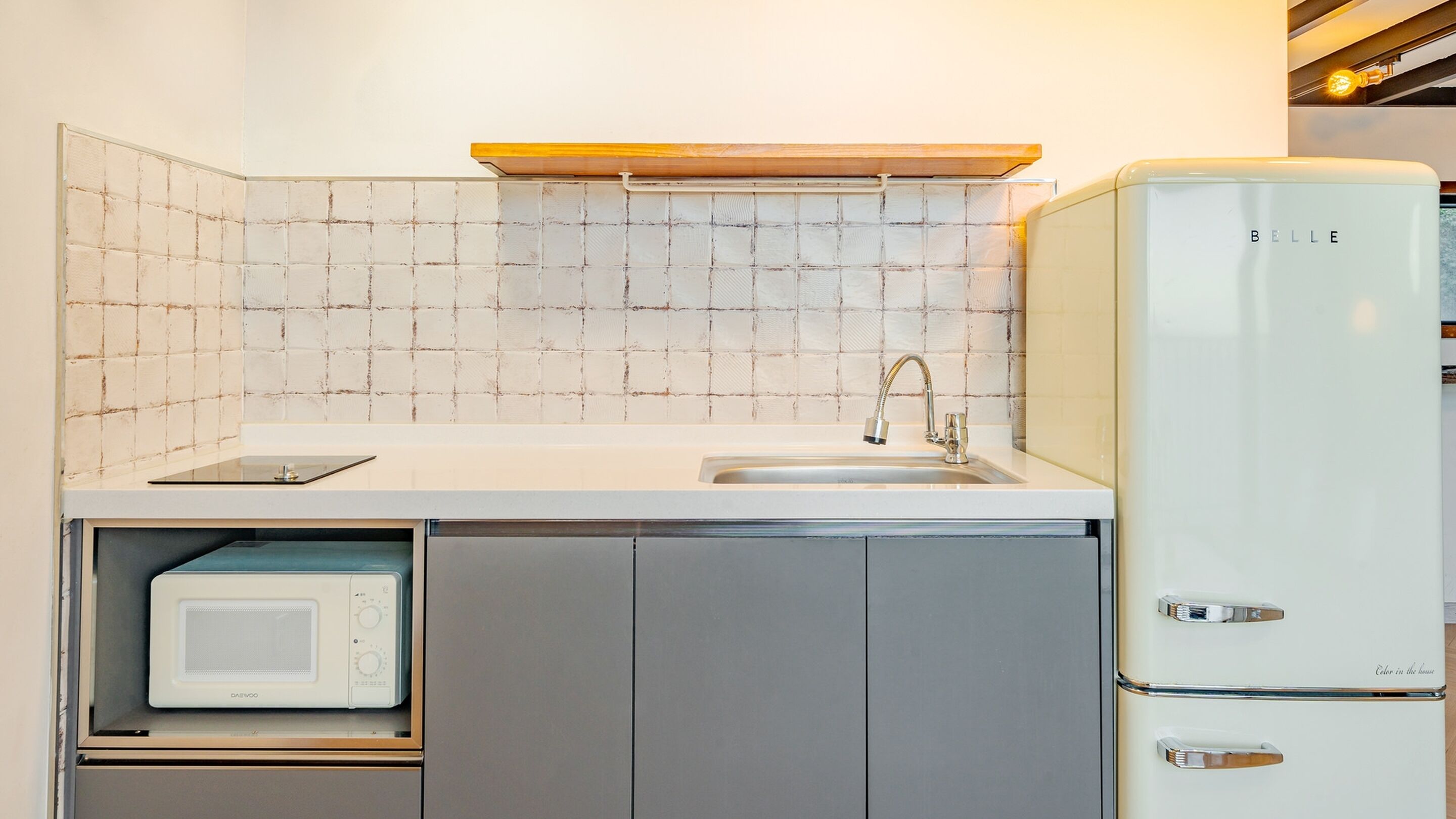 A compact kitchen with a built-in microwave, a sink with a modern faucet, and a white refrigerator.