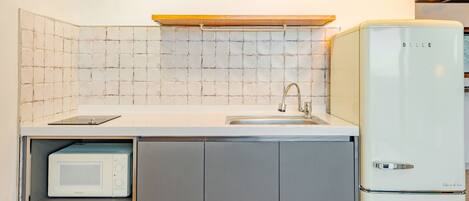 A compact kitchen with a built-in microwave, a sink with a modern faucet, and a white refrigerator.
