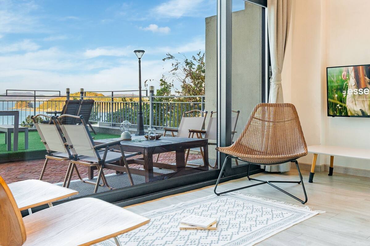 A modern room with a balcony, a TV, and a view of the outdoors.