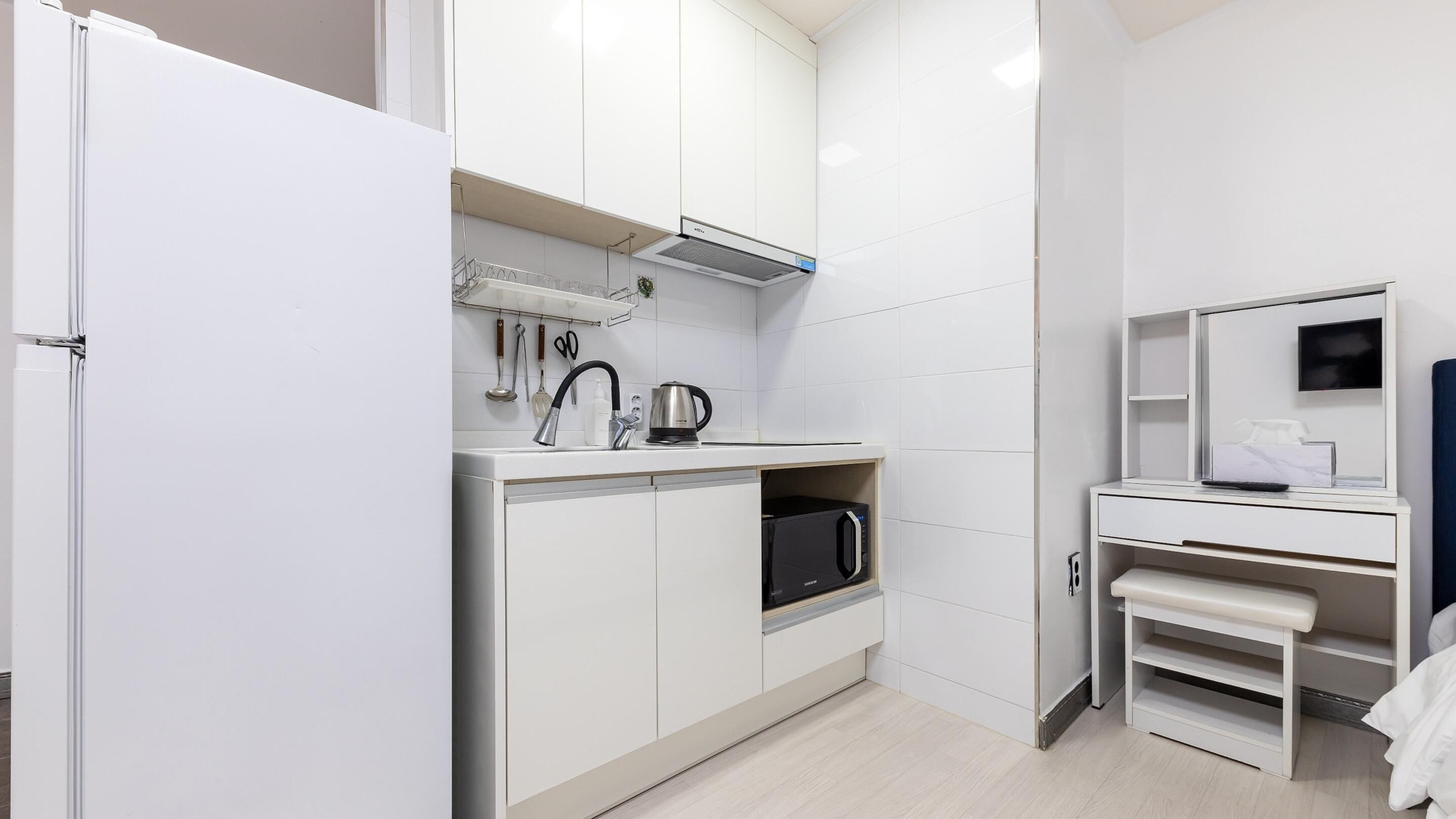 Une cuisine moderne avec des meubles blancs, un four à micro-ondes et une bouilloire.