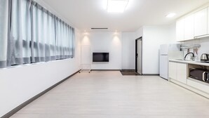 A modern kitchen with a flat-screen TV, white cabinets, and a coffee machine. - Yeosu Onueli Pension (Yeosu)