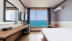A hotel room with a bed, desk, TV, and a view of the sea. - Yangyang Eight (Yangyang)