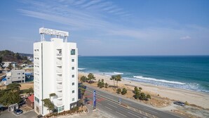 A white hotel with a sign reading "EIGHTHOTEL" overlooking a beach with a road in the foreground. - Yangyang Eight (Yangyang)