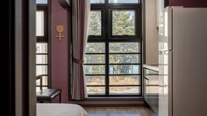 A bedroom with a bed, a window with curtains, a wooden wall decoration, and a white refrigerator. - Samcheok Lamer Pension (Samcheok)
