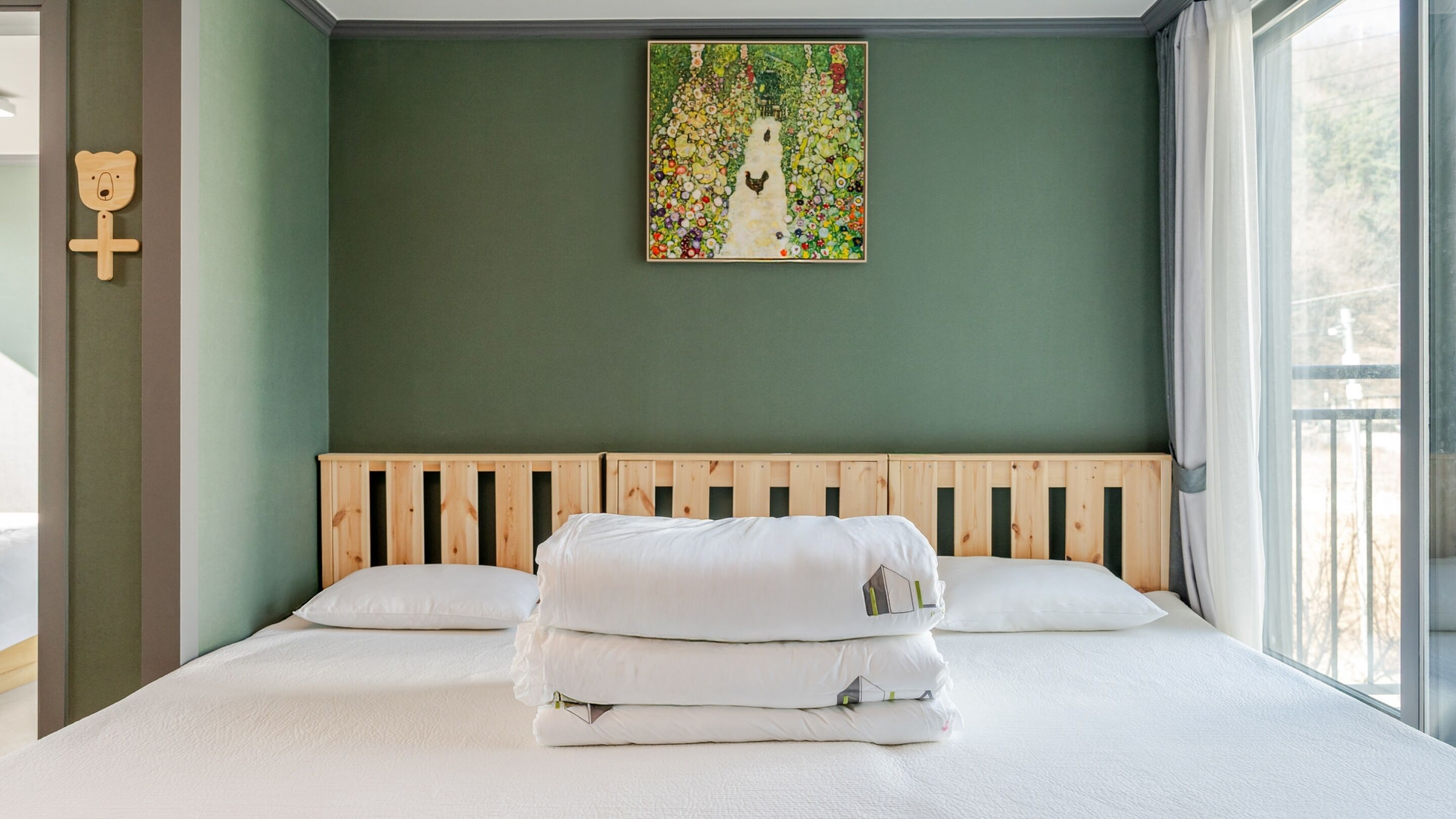 Un dormitorio con cabecera de madera, cama con ropa blanca y un cuadro de colores en la pared.