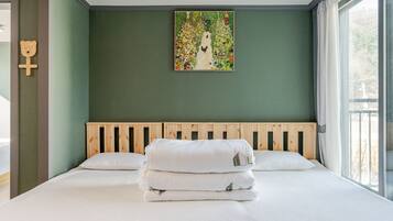 Un dormitorio con cabecera de madera, cama con ropa blanca y un cuadro de colores en la pared.