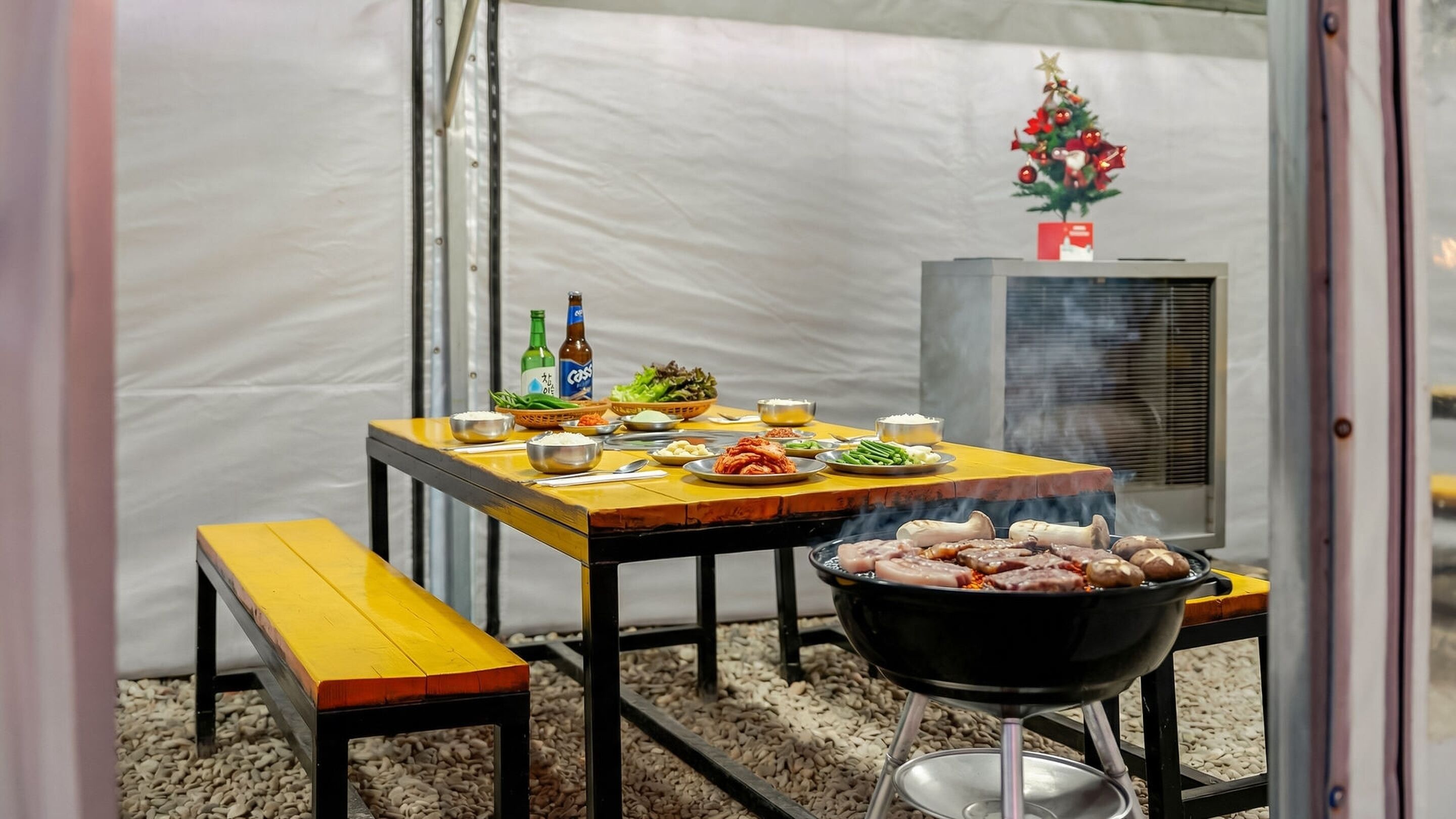 A dining area with a table set for a meal, a grill, and a Christmas tree decoration.