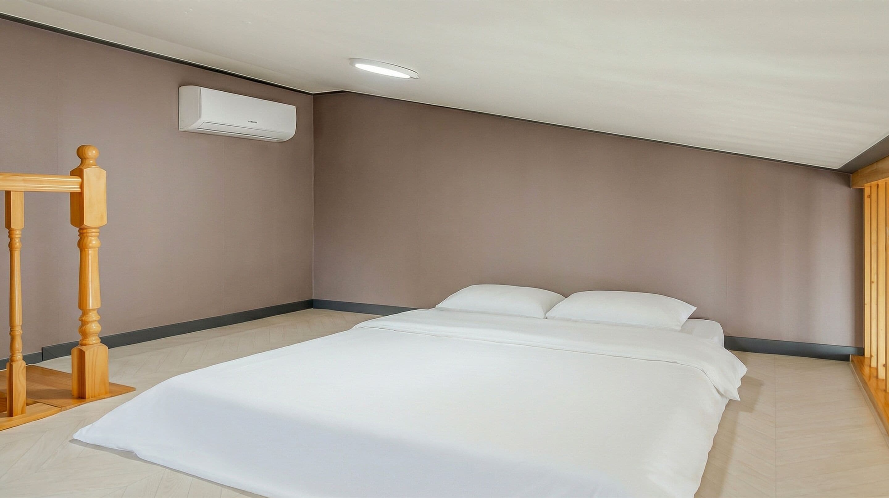 A bedroom with a bed, a wooden chair, and an air conditioning unit on the wall.