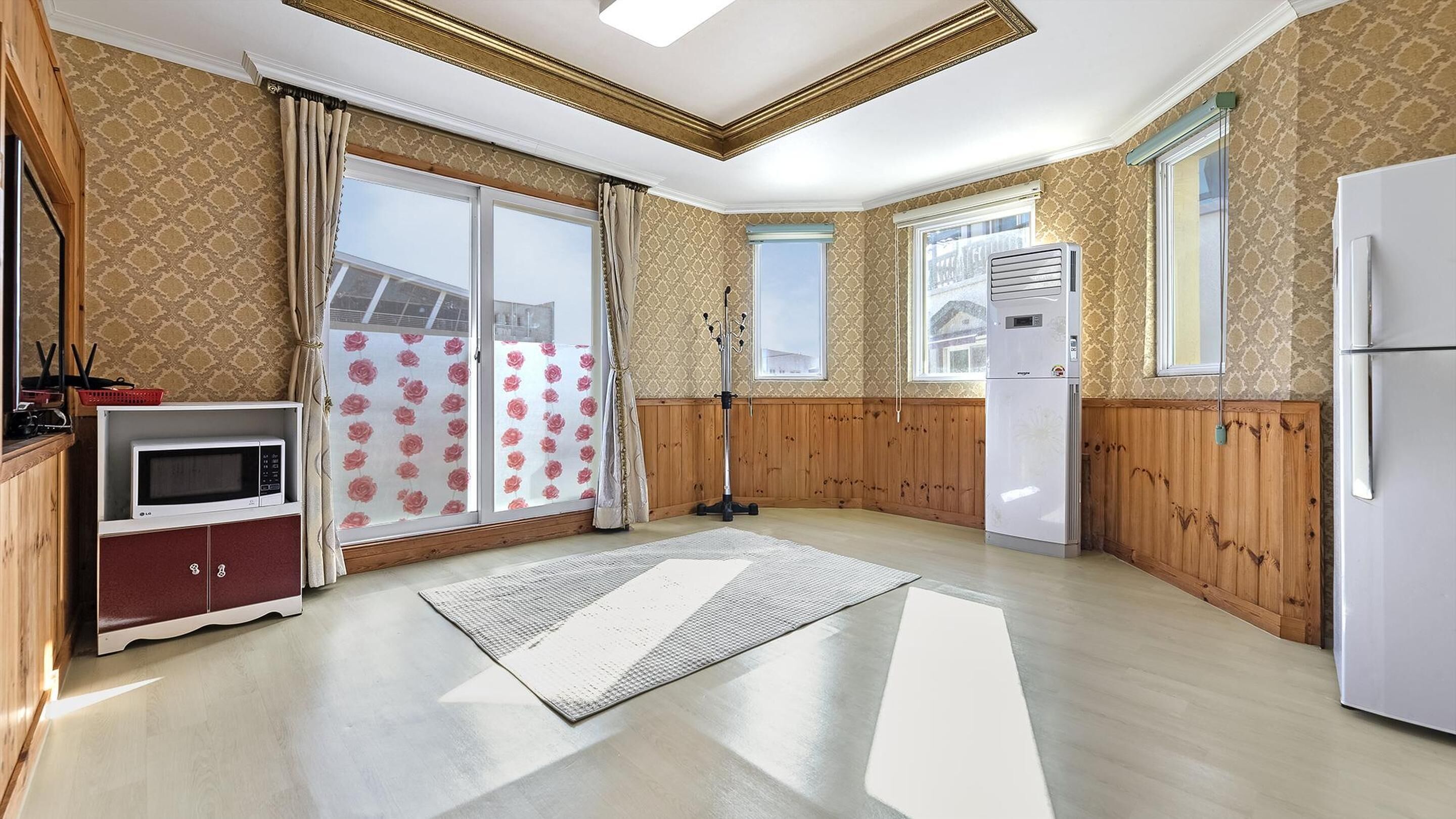 A kitchen with wooden paneling, a microwave, a refrigerator, and a large window with a view.