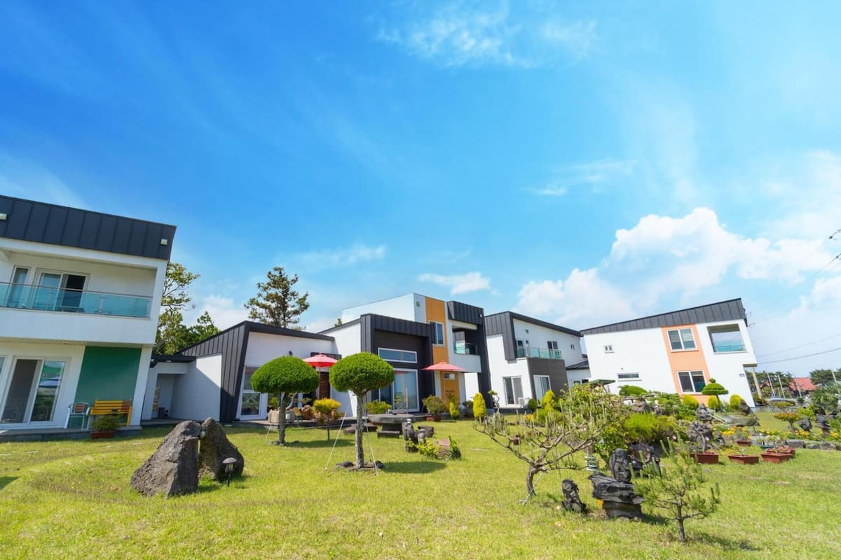 A modern residential complex with multiple two-story houses, a well-maintained lawn, and a clear blue sky.