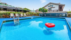 A swimming pool with a red heart-shaped float, a ladder, and lounge chairs.