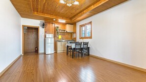 A spacious kitchen with wooden flooring, a dining area with a table and chairs, and a wooden ceiling with exposed beams.