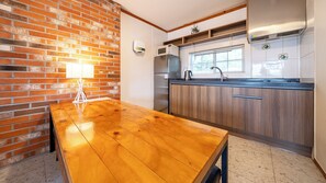 A kitchen with a wooden table, a brick wall, and a stainless steel refrigerator. - Gapyeong Botanical Pension (Gapyeong)