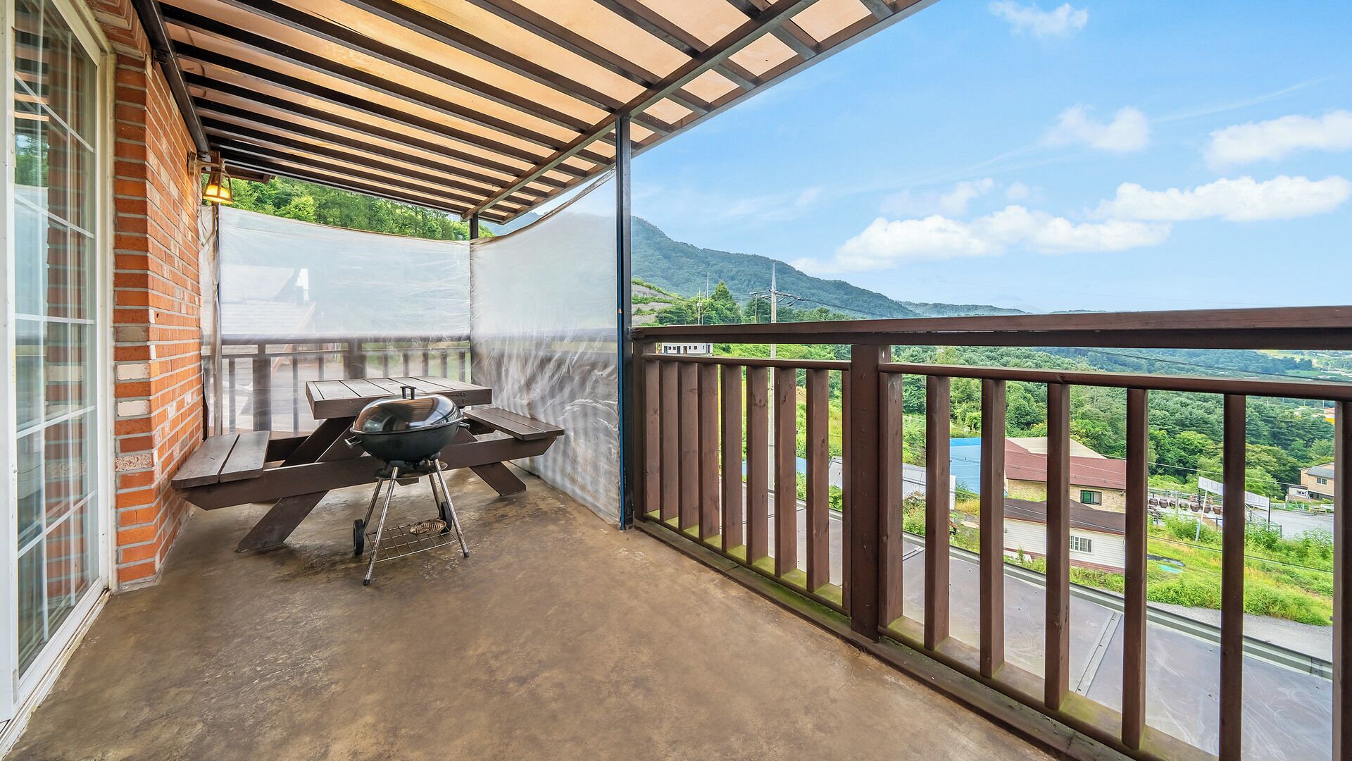Un balcon équipé d’un barbecue, d’une table et offrant une vue sur un paysage vallonné.