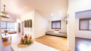 Un interior moderno con comedor, una zona de estar con sofá y banco, y una kitchenette.