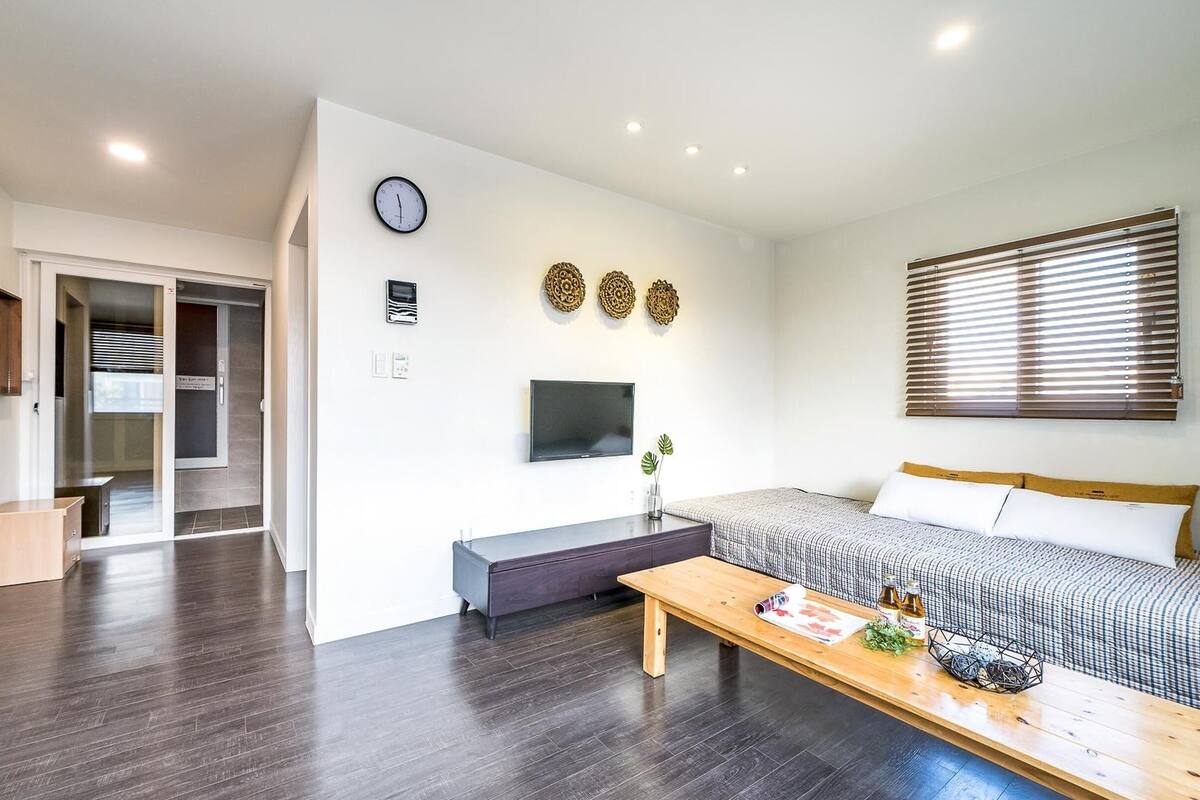 A modern living room with a sofa, a coffee table, a TV, and a clock on the wall.