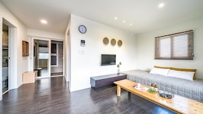 A modern living room with a sofa, a coffee table, a TV, and a clock on the wall. - Busan the Pension 502 (Busan)