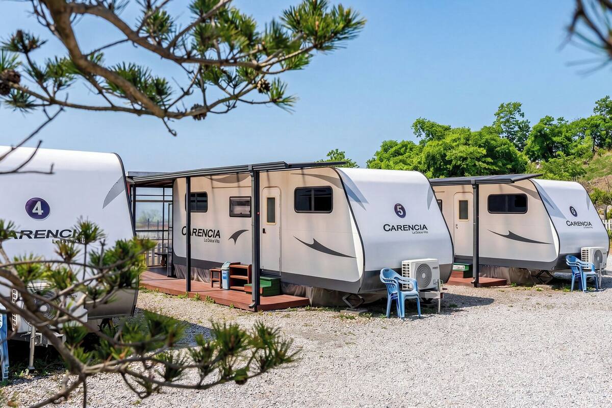 A row of caravan-style RVs labeled with numbers 4 to 6, each with a covered entrance and a small outdoor seating area.