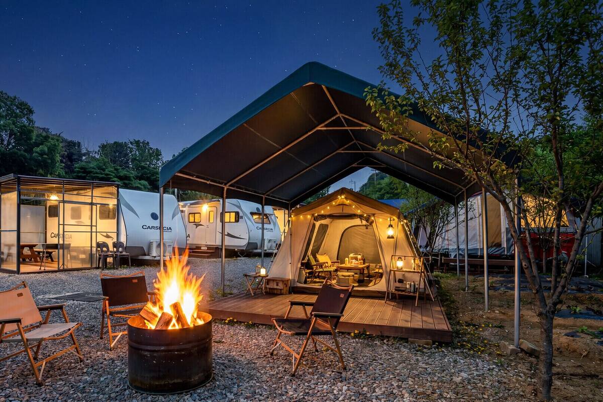 A campsite with a fire pit, outdoor seating, and RVs.