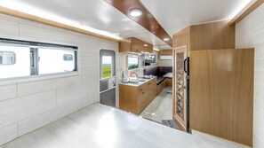 Une cuisine moderne pour camping-car, équipée d’une fenêtre, d’un évier et d’un réfrigérateur.
