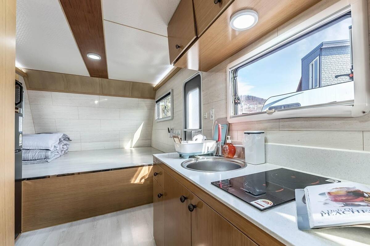 A compact kitchen with a window, a sink, and a magazine on the counter.