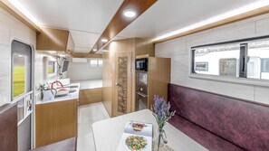 Une cuisine compacte pour camping-car, équipée d’un évier, d’une cuisinière et d’un réfrigérateur.