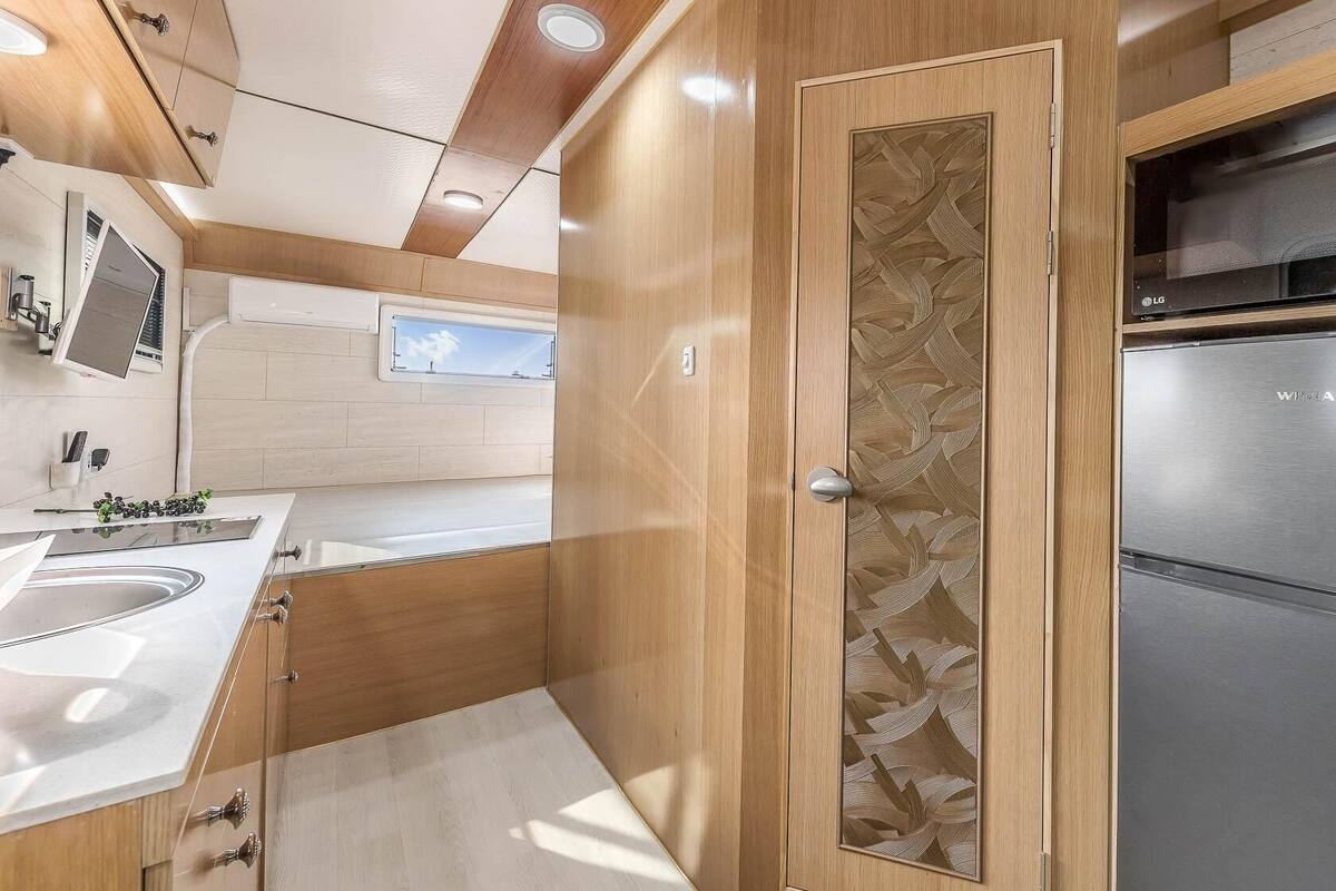 A compact kitchen with a microwave, refrigerator, and a window above the sink.