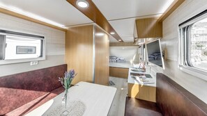 Un intérieur de camping-car compact comprenant un coin cuisine, un espace repas et un coin salon.