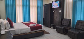Una habitación de hotel con cama, televisor, sofá y armario.