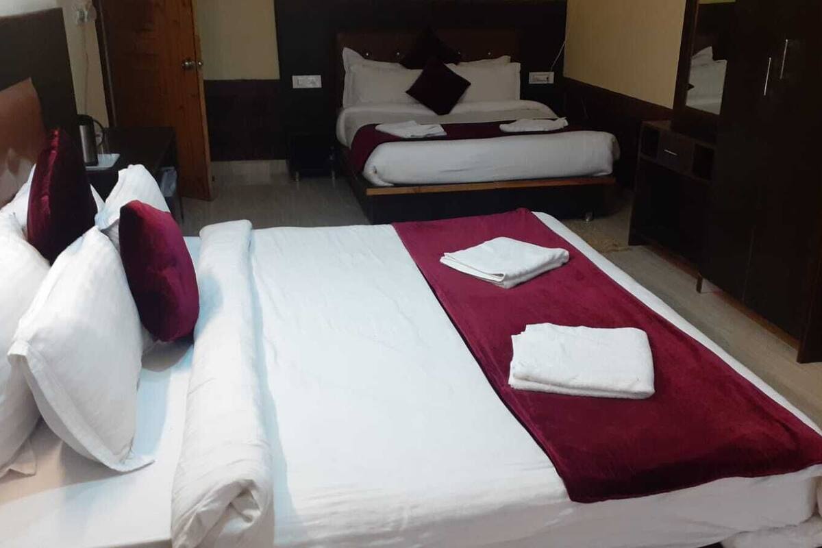 A hotel room with a large bed, a smaller bed, a wardrobe, and a desk.