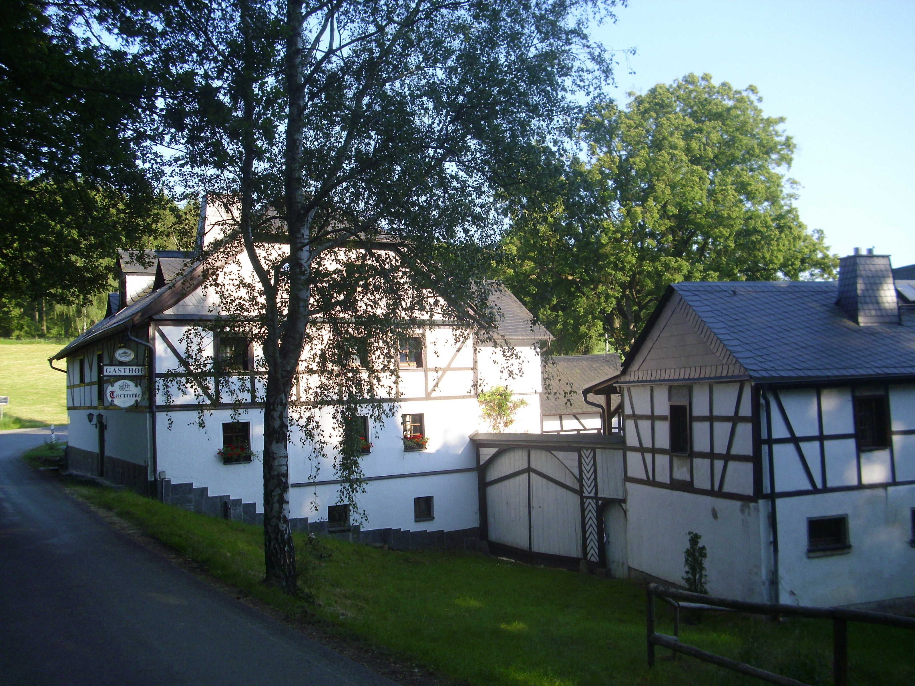 A traditional half-timbered building with a sign reading 'GASTHOF' and a small adjacent structure.