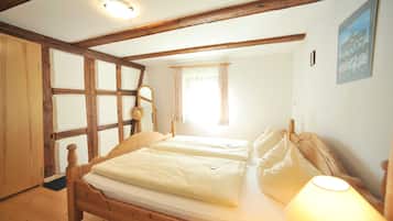 Une chambre à coucher avec un lit en bois, une table de chevet, une lampe et une fenêtre avec des rideaux.