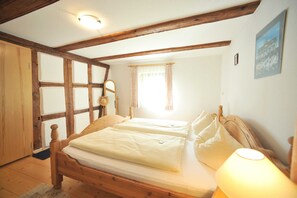Ein Schlafzimmer mit einem hölzernen Bett, einem Nachttisch, einer Lampe und einem Fenster mit Vorhängen.