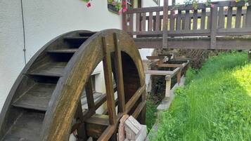 Ein rustikales Gebäude mit einem großen Wasserrad, Holzstufen und einer Holzbrücke.
