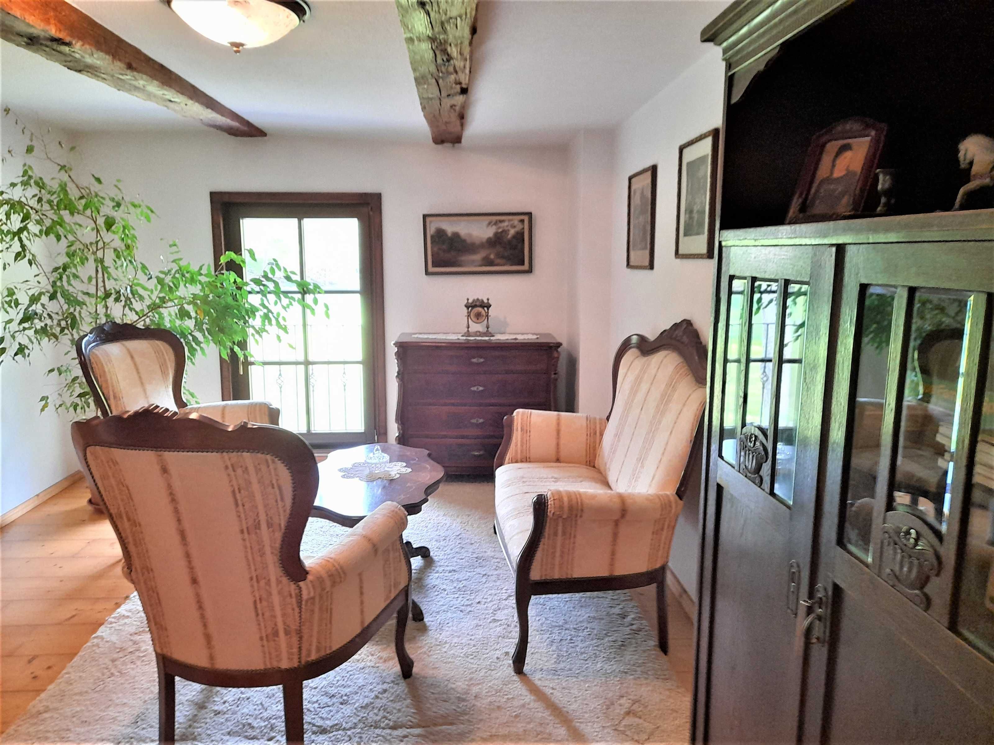 A room with two upholstered chairs, a wooden cabinet, a small table, and a window with a view.