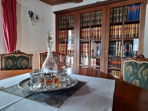 A room with a wooden table, a glass decanter, and a bookshelf filled with books.