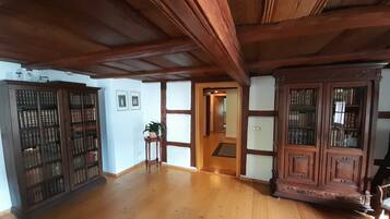A spacious room with wooden flooring, a large wooden cabinet with glass doors, and a small table with a plant.