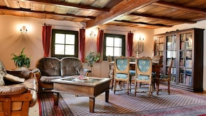 A traditional room with a wooden ceiling, leather chairs, a wooden coffee table, and a bookshelf.