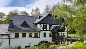 A traditional half-timbered house with a stone pathway leading to a wooden bridge.