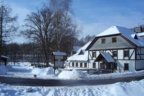 En snötäckt byggnad med en skylt som visar texten ”Gastrop Teichmühle”.