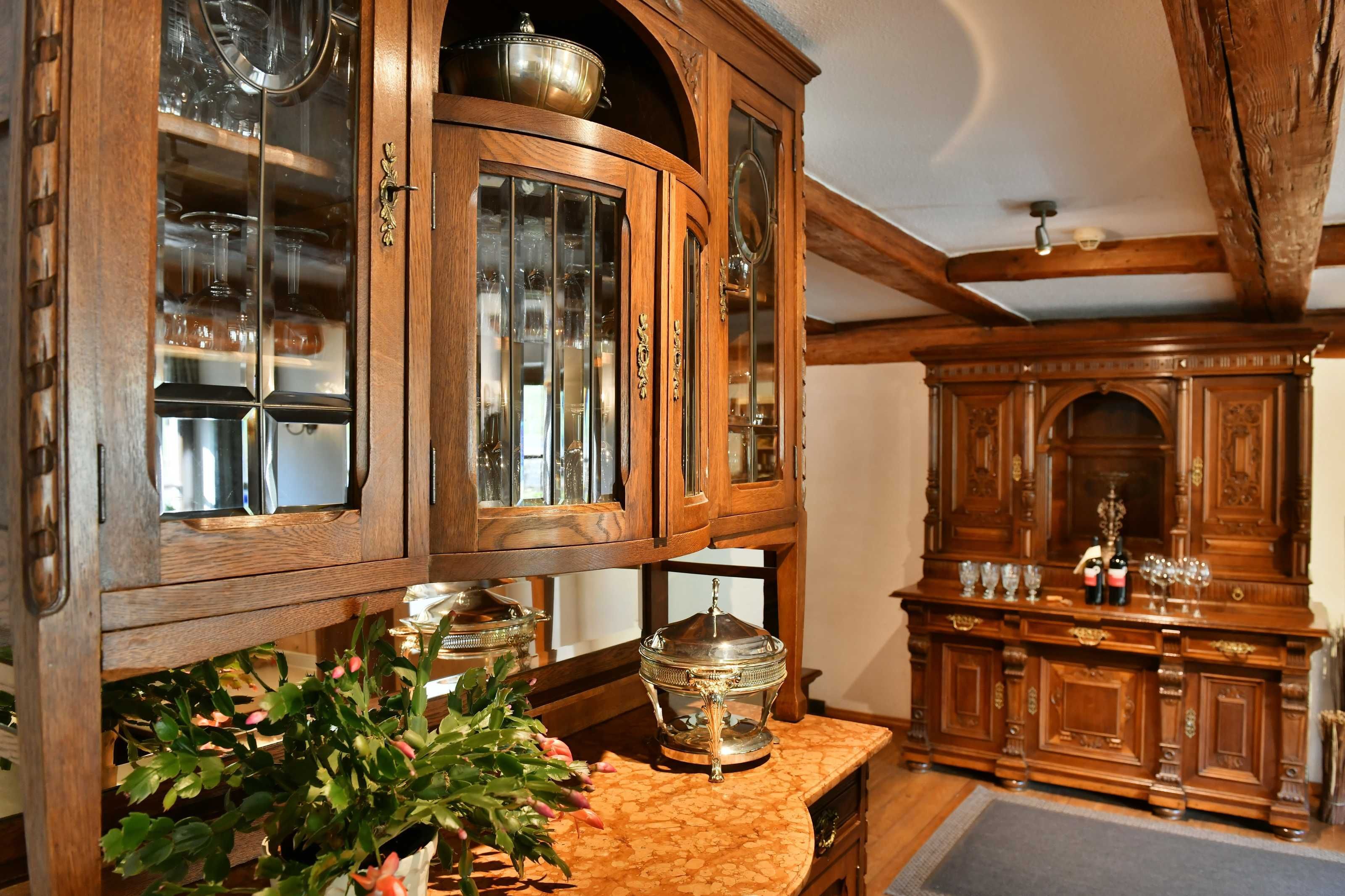 Ein Holzkabinett mit Glastüren, ein kleiner Tisch mit einer Pflanze und eine Weinflasche.