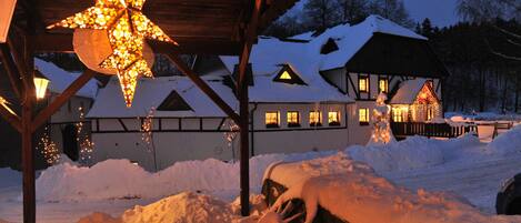 A snow-covered building with a star-shaped light fixture, wooden beams, and a snow-covered bench.